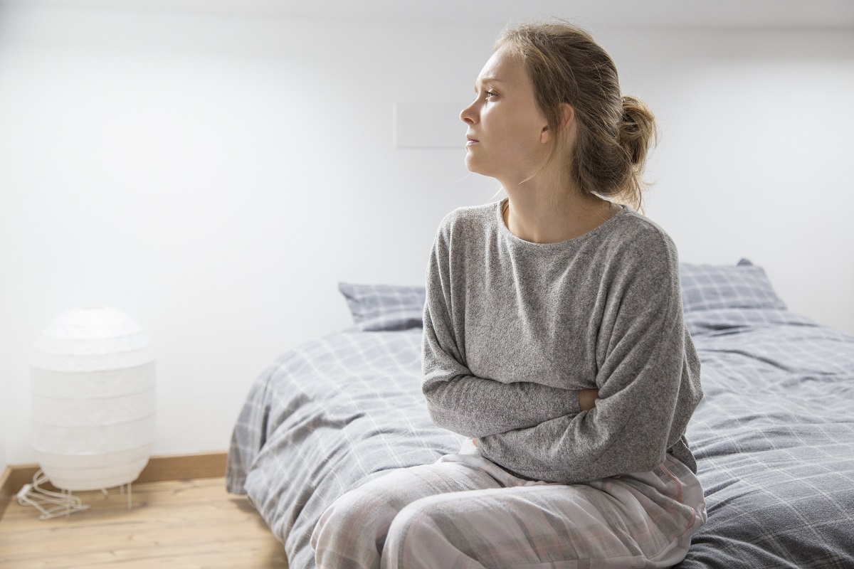 mujer con las manos en el estomago sufriendo de dolor mirando un lado